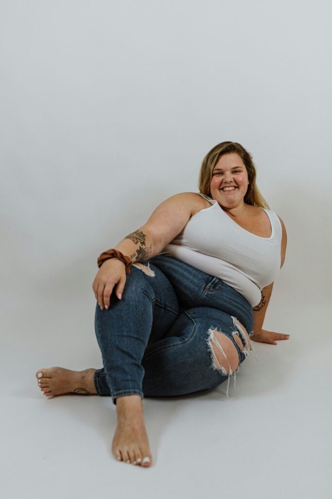 A full figured woman in a white tank top and jeans 