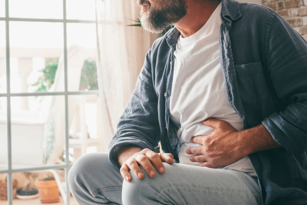 Hand of mature guy holding abdomen suffering from ache