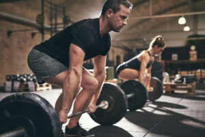 Sporty man and woman are about to lift barbells in gym.